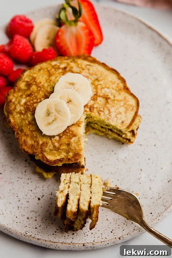 A fork piercing a soft, fluffy 3-ingredient banana pancake, showcasing its perfectly cooked, tender texture.