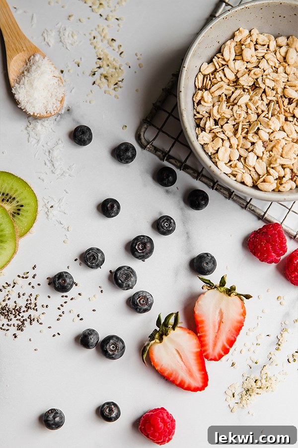 An artfully arranged collection of fresh fruits, crunchy nuts, and superfood seeds for smoothie bowl toppings. Juicy berries, vibrant kiwi, tropical mango, and various seeds are spread across a elegant marbled surface.
