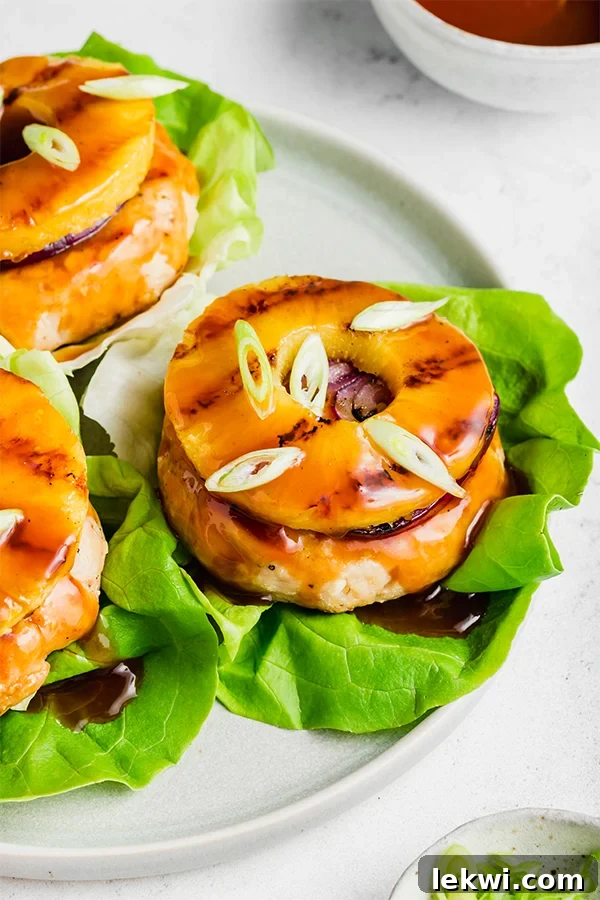 An appetizing overhead shot of a sweet and sour chicken burger, perfectly assembled with a grilled pineapple slice and vibrant green onions, emphasizing its gourmet yet healthy appeal.