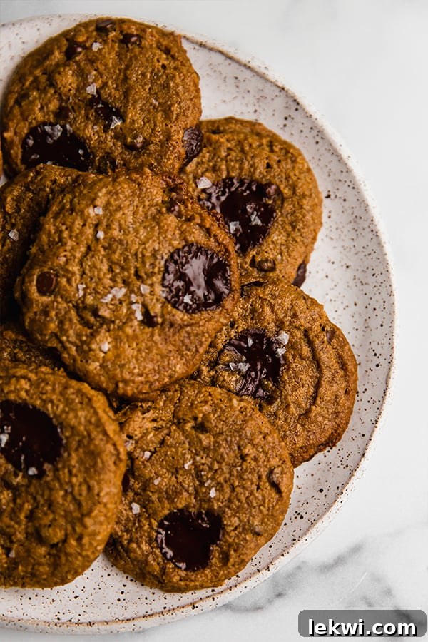 Close-up shot of two flourless almond butter cookies on a minimalist plate, highlighting their appealing texture.