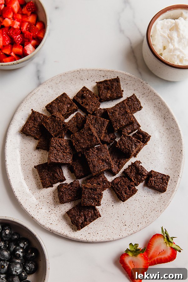 Brownie chunks on plate with other toppings in bowls, ready for parfait assembly.