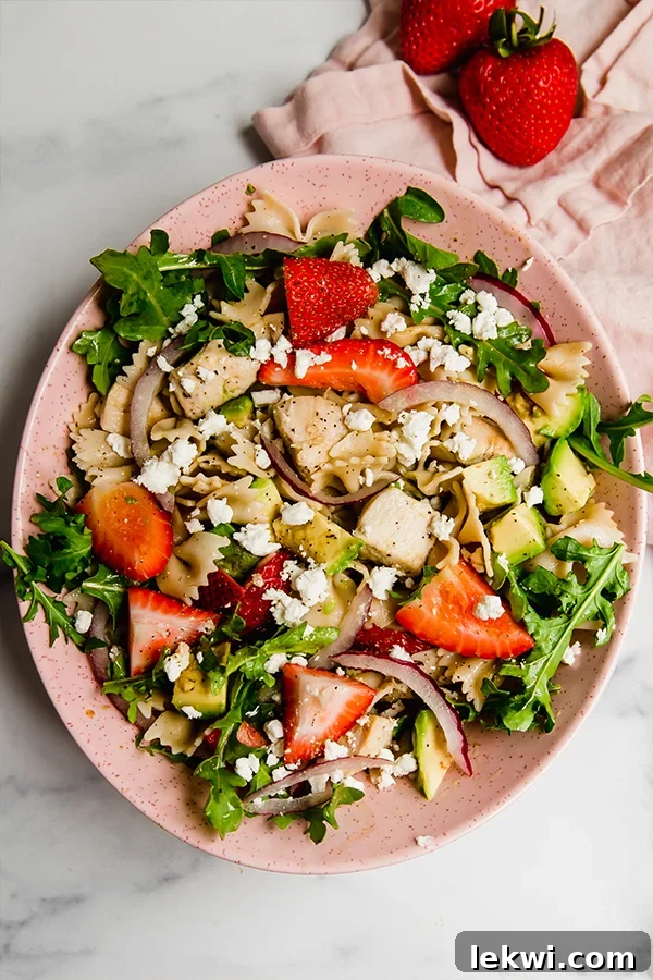 Vibrant Strawberry Balsamic Pasta Salad served on a pink plate, showcasing fresh ingredients.