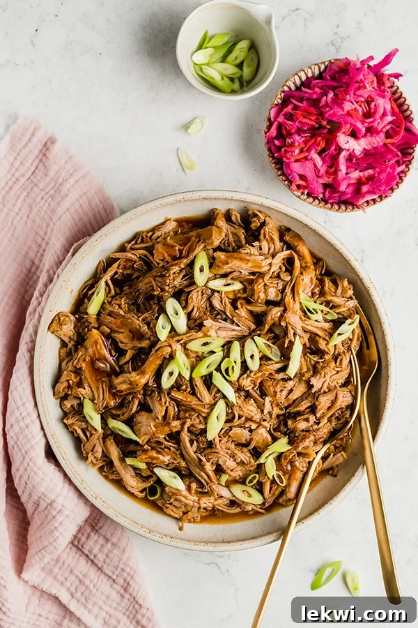 Barbecue pulled pork in a bowl, garnished with fresh herbs.