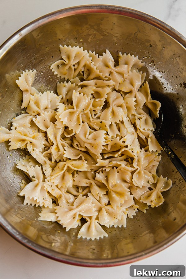 Al dente pasta tossed with olive oil and Italian seasoning in a large mixing bowl.