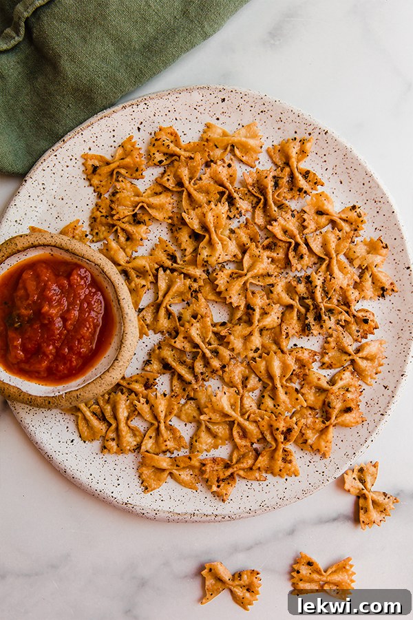 Crispy homemade pasta chips beautifully arranged around a bowl of marinara dipping sauce.