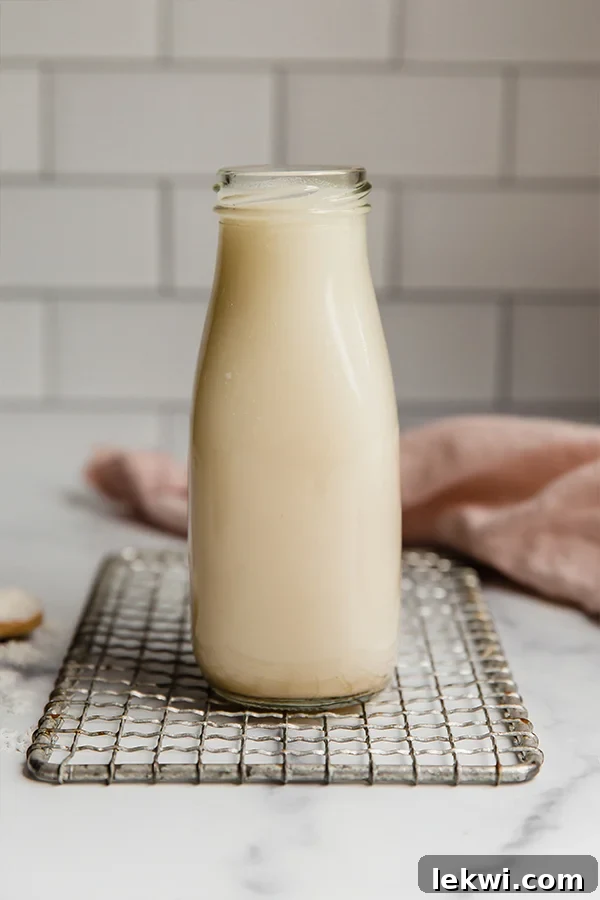 A glass jar of freshly made coconut milk, invitingly creamy, showcasing its homemade goodness.