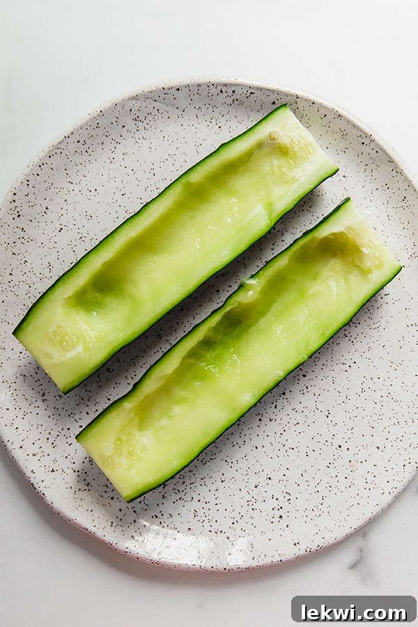 Hollowed-out cucumber halves on a plate, ready for filling.