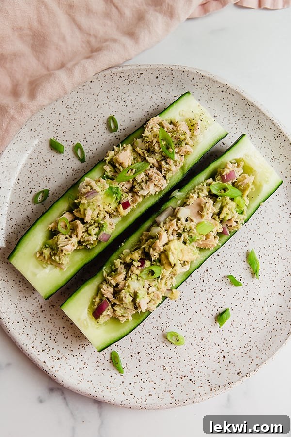 Hollowed-out cucumbers filled with tuna salad, garnished with green onion.