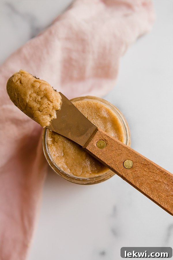 A glass jar filled with homemade tigernut butter, with a knife poised to spread it, suggesting its readiness for use.
