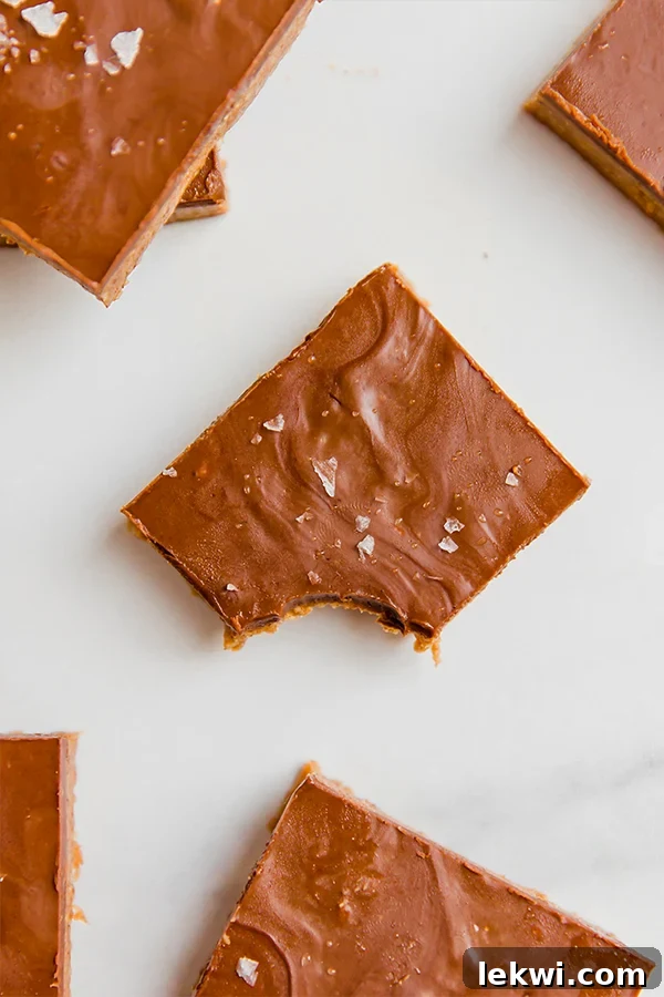 A delectable Chocolate almond butter bar with a single bite missing, revealing its rich, layered interior, presented on a clean surface.