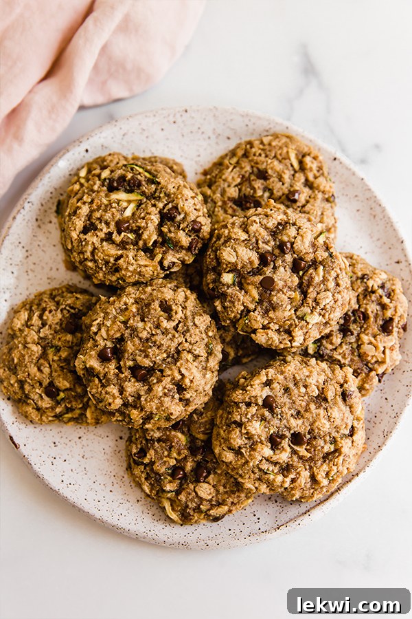 Top view of perfectly baked oatmeal zucchini cookies stacked artfully on a plate, highlighting their inviting texture and generous chocolate chips.