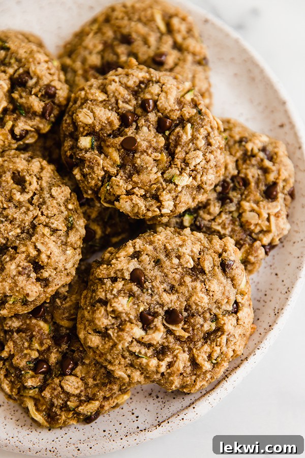 A stack of golden-brown oatmeal zucchini cookies on a plate, showcasing their inviting texture and generous chocolate chips, ready to be enjoyed.