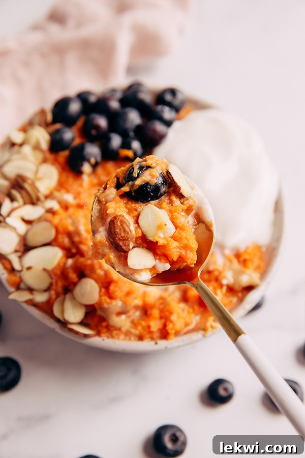 Spoonful of creamy sweet potato breakfast bowl with toppings.