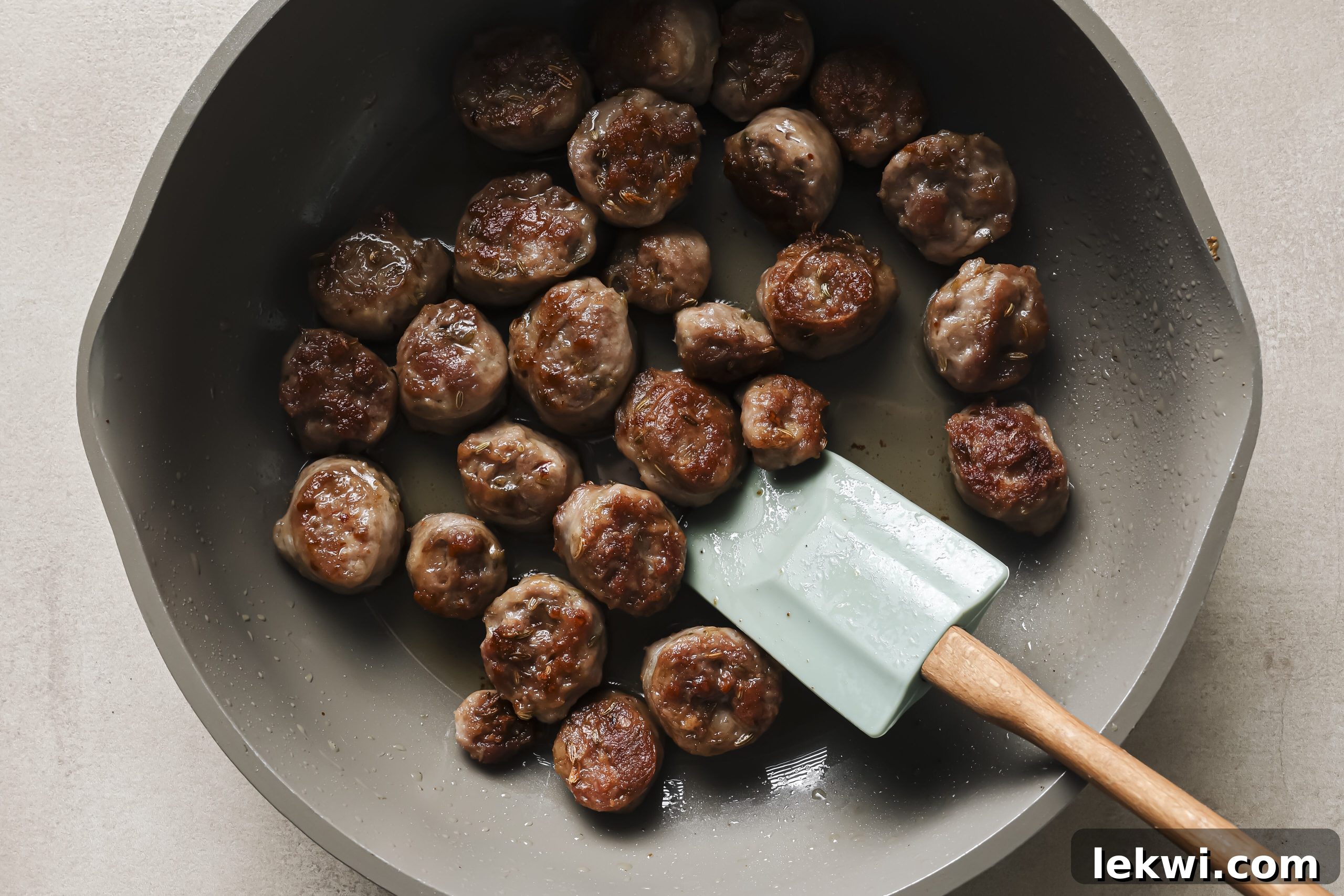 Sausage slices browning beautifully in a hot skillet, ready to add savory depth to the dish.