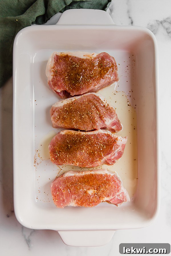 4 boneless pork chops seasoned and ready to bake in a baking dish