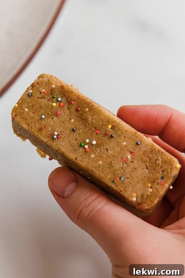 Close-up of a protein bar held in hand, highlighting its texture and deliciousness.