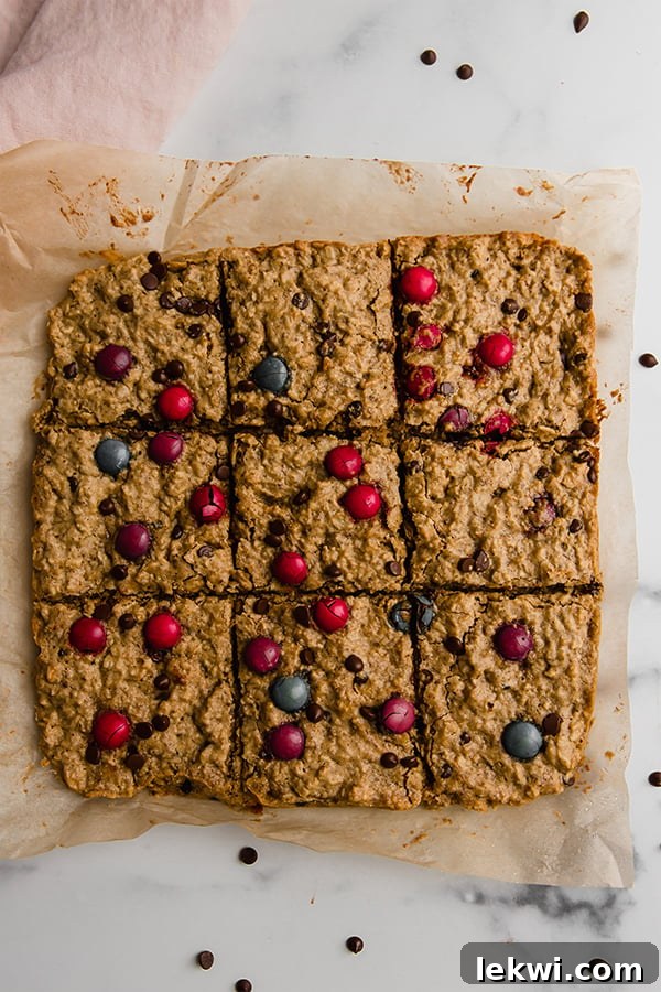 Top-down view of Monster Cookie Oatmeal Breakfast Bars freshly baked and cut on a kitchen counter, ready to be enjoyed.