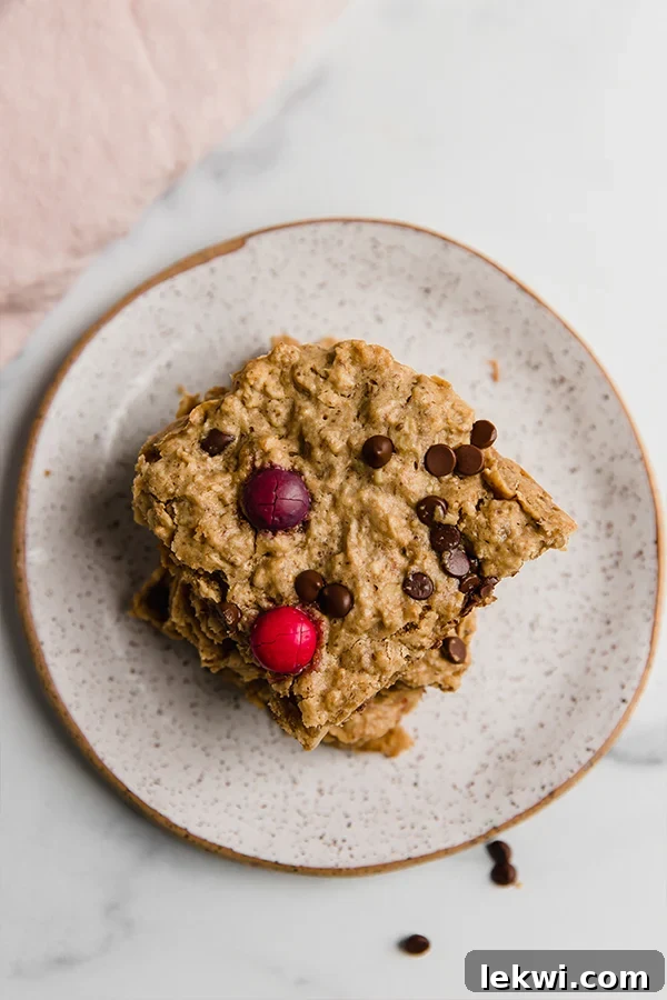 Close-up of a single Monster Cookie Oatmeal Breakfast Bar square resting on a plate, highlighting its soft texture and colorful inclusions.