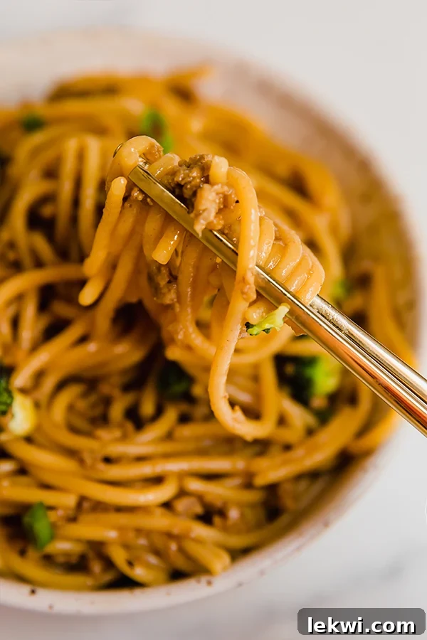 Close-up shot of Mongolian ground beef with noodles served in a vibrant bowl, ready to be enjoyed with chopsticks.