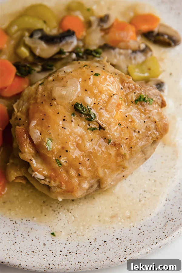 A serving of creamy chicken fricassee plated with a side of green vegetables, showcasing the rich golden chicken and vibrant sauce.