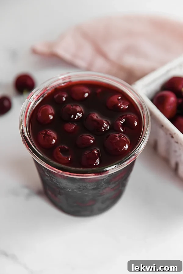 Glass of vibrant homemade maraschino cherries, glistening in their natural syrup, ready to be enjoyed.