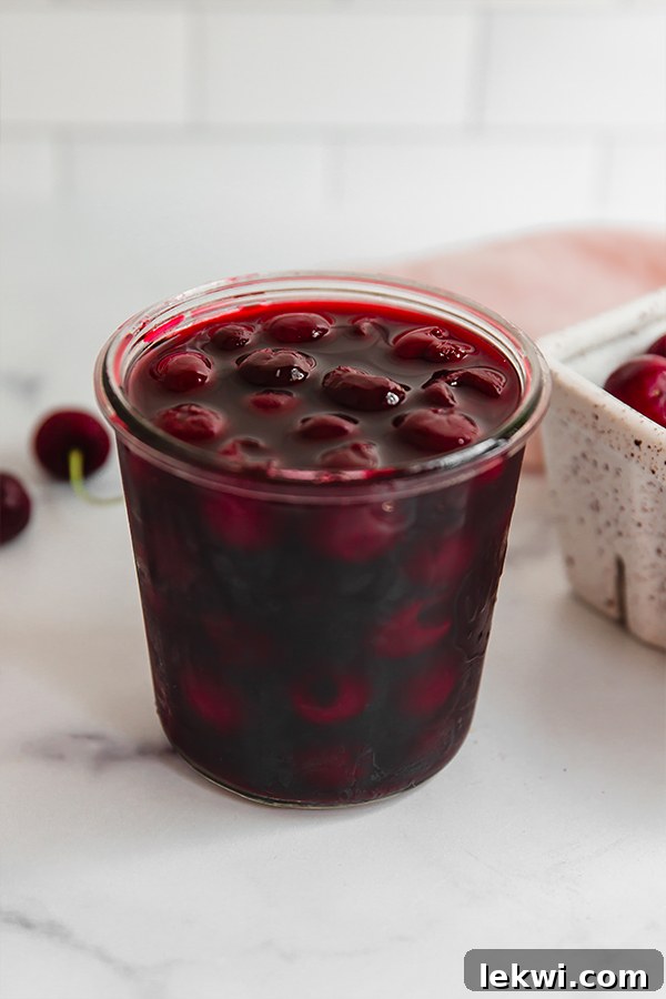 Homemade maraschino cherries beautifully displayed in an elegant glass jar, highlighting their natural and rich color.