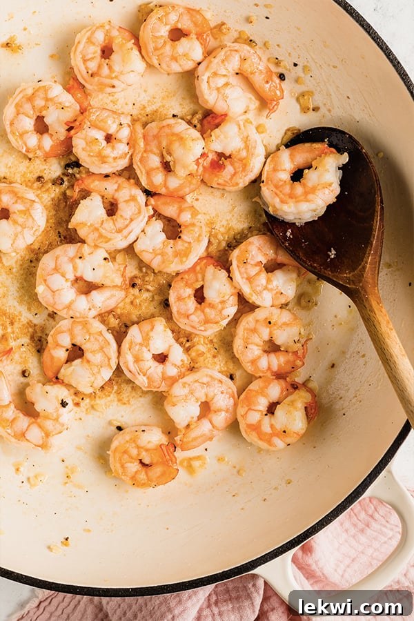 Shrimp cooking in a pan with a wooden spoon