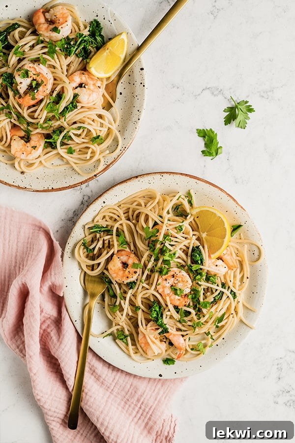 Two plates of lemon garlic shrimp pasta, garnished and ready to serve.