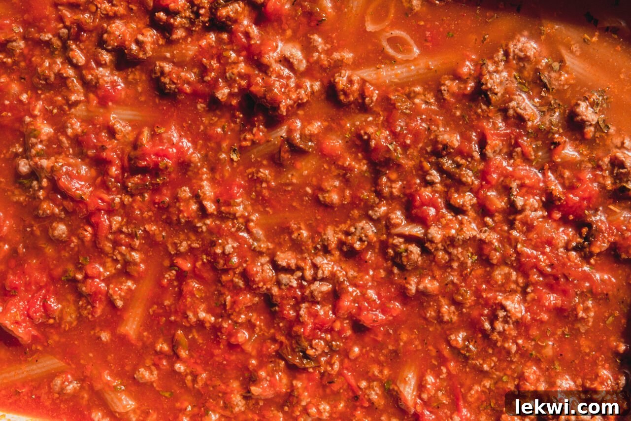 All ingredients stirred together in the baking dish, with pasta submerged in liquid, ready for baking.