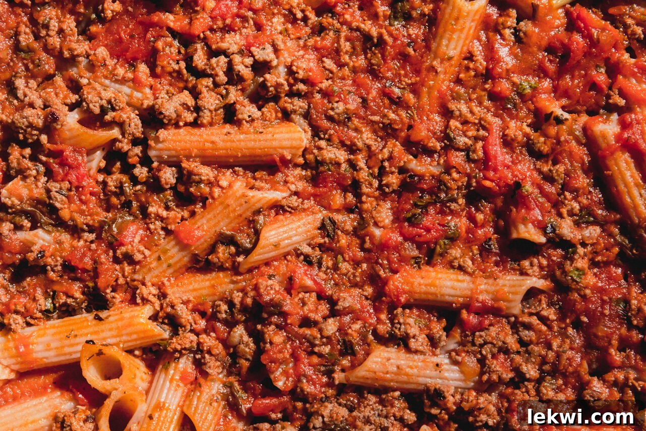 Baked pasta bake with cooked pasta and meat sauce, after removing the cover from the casserole dish.