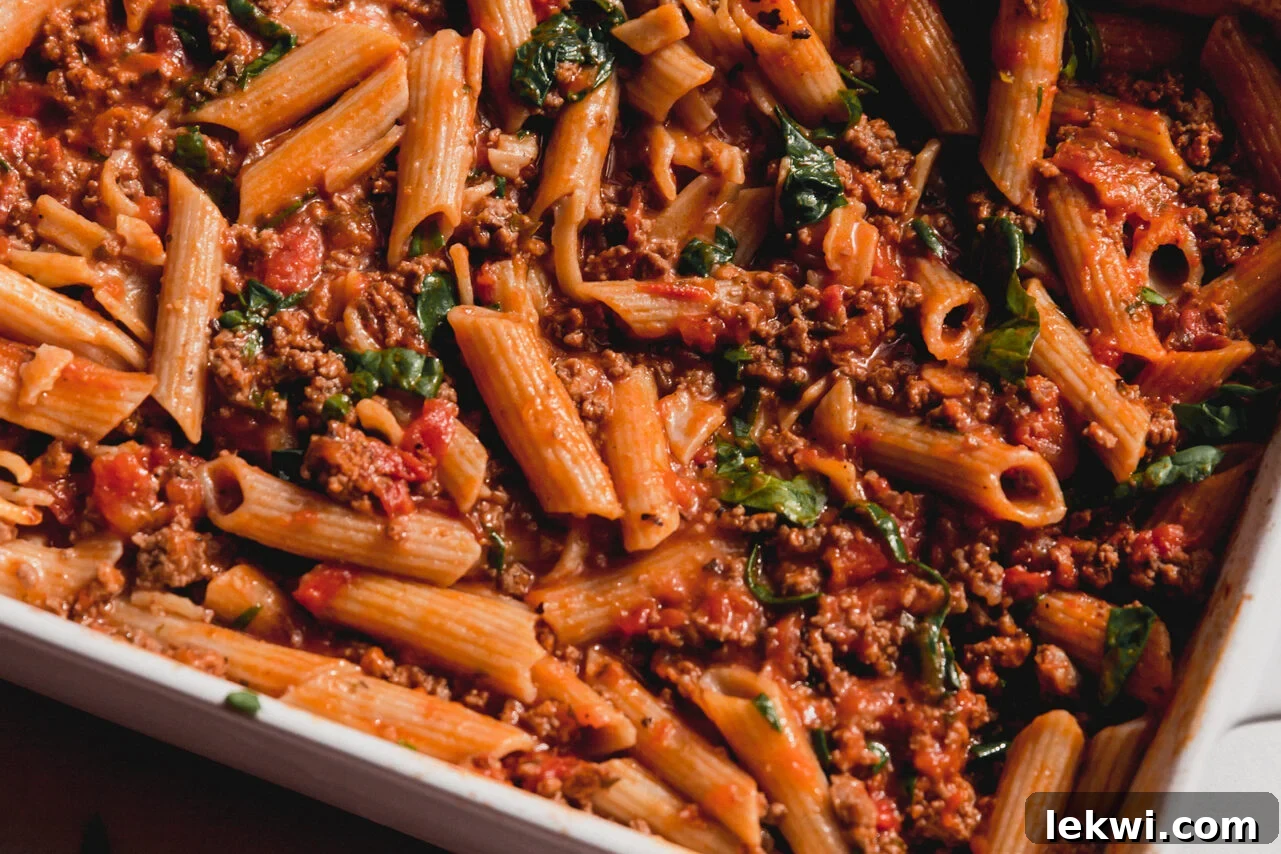 Wilted spinach stirred into the hot pasta bake, adding vibrant green color.