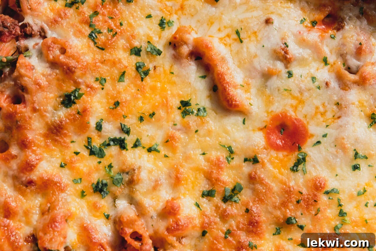 The finished no boil pasta bake, topped with melted cheese and fresh chopped parsley, ready to serve.