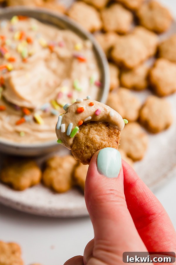 A Dunkaroo cookie with icing and sprinkles being lifted by a hand.