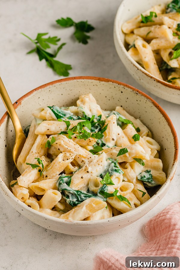 A bowl of Easy Penne Alfredo with chopped parsley on top, ready to be eaten. 