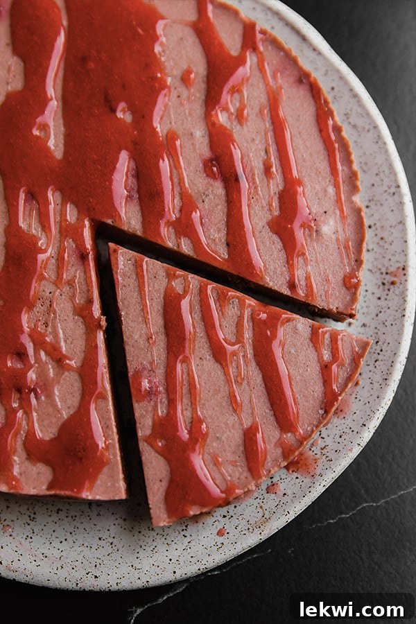 A slice of red velvet cheesecake with strawberry drizzle, ready to serve.