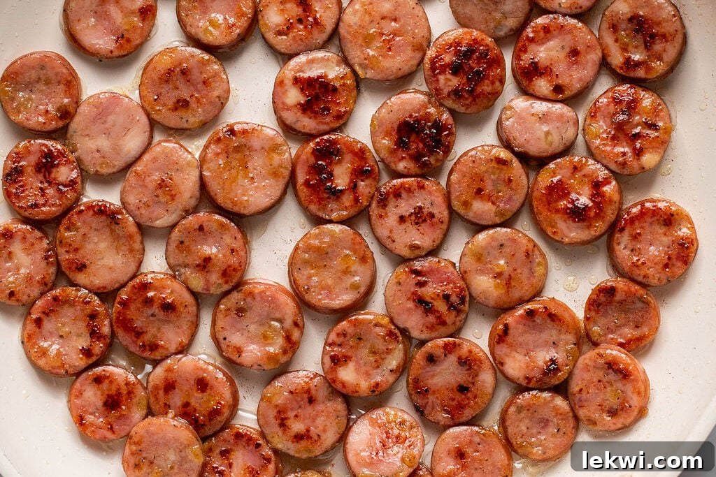 Browning sliced chicken sausage in a pan.