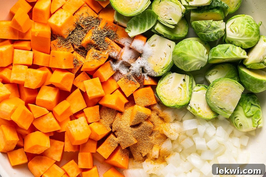 Uncooked sweet potato, brussels sprouts, and onion in a pan, before sautéing.