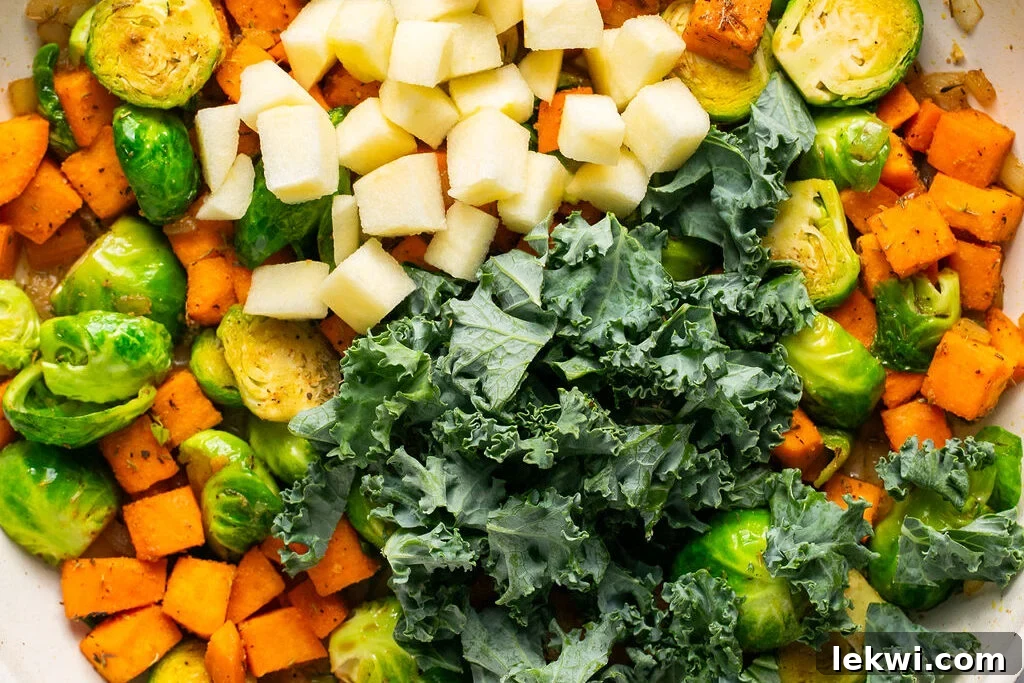 Cooked sweet potato, brussels sprouts, and onion in a pan, tender and slightly caramelized.