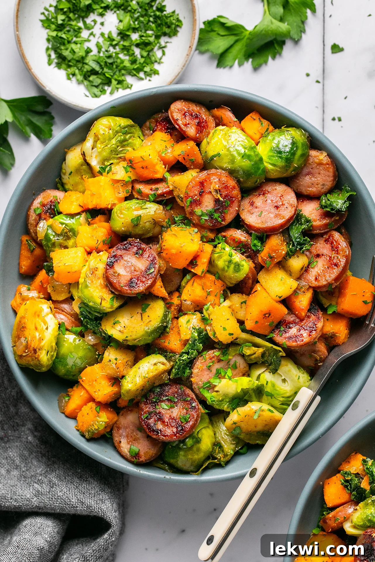Apple chicken sausage skillet in a large bowl, garnished with fresh parsley.