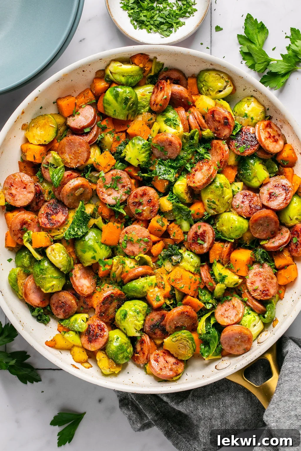 Apple, chicken sausage, and colorful vegetables in a large white bowl.