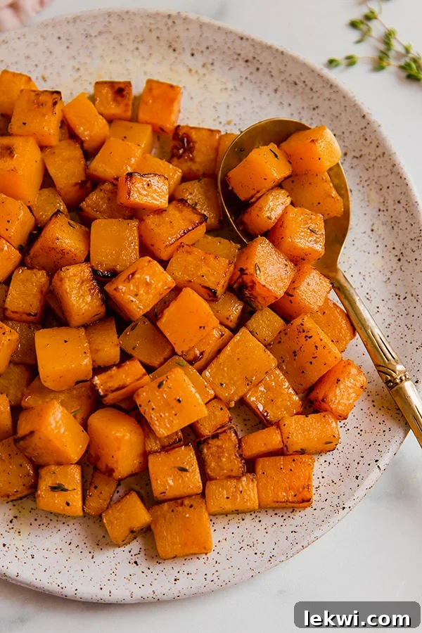 Golden brown air-fried butternut squash on a plate, ready to be served, with a spoon nearby.