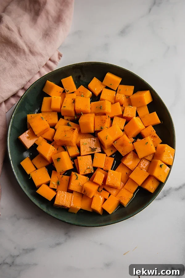 Freshly cubed butternut squash in a mixing bowl, ready for seasoning.