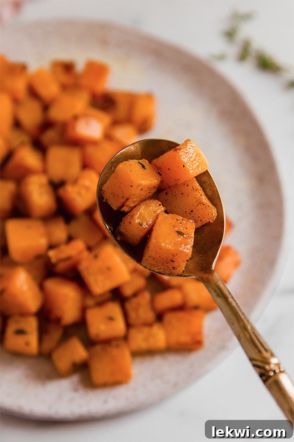 A single piece of perfectly cooked cubed butternut squash balanced on a spoon.