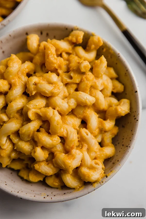 Bowl of noodles generously coated with creamy butternut squash pasta sauce, garnished with fresh sage leaves.