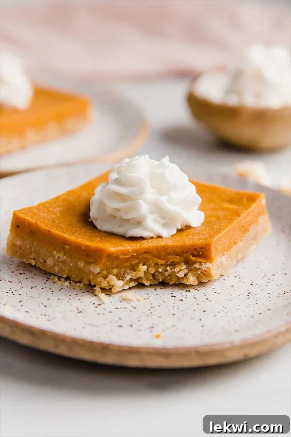 A delectable Pumpkin Pie Bar with a unique cereal crust, a small bite missing, showcasing its creamy filling.