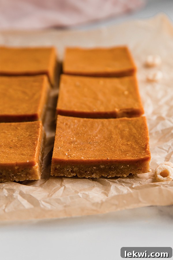Perfectly sliced Pumpkin Pie Bars, showcasing the distinct cereal crust and creamy pumpkin filling, arranged on parchment paper.