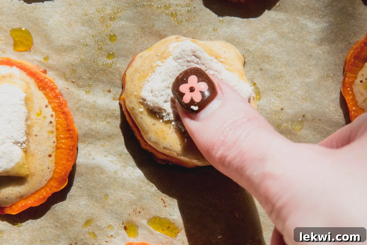 A thumb pressing the marshmallow into the sweet potato bite.