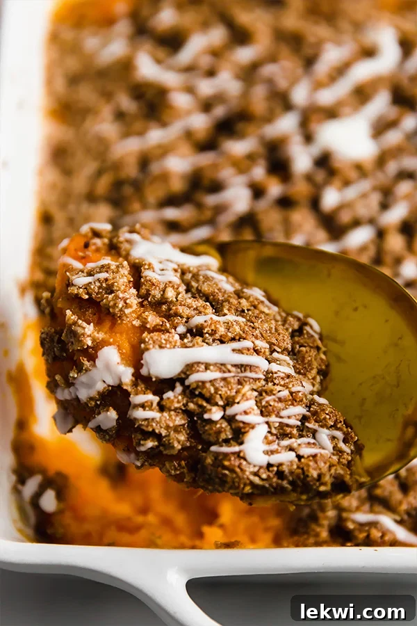 A close-up shot of a spoonful of sweet potato casserole, showcasing the creamy base and crumbly streusel texture.