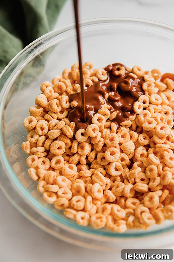 Chocolate pouring over cereal in a bowl.