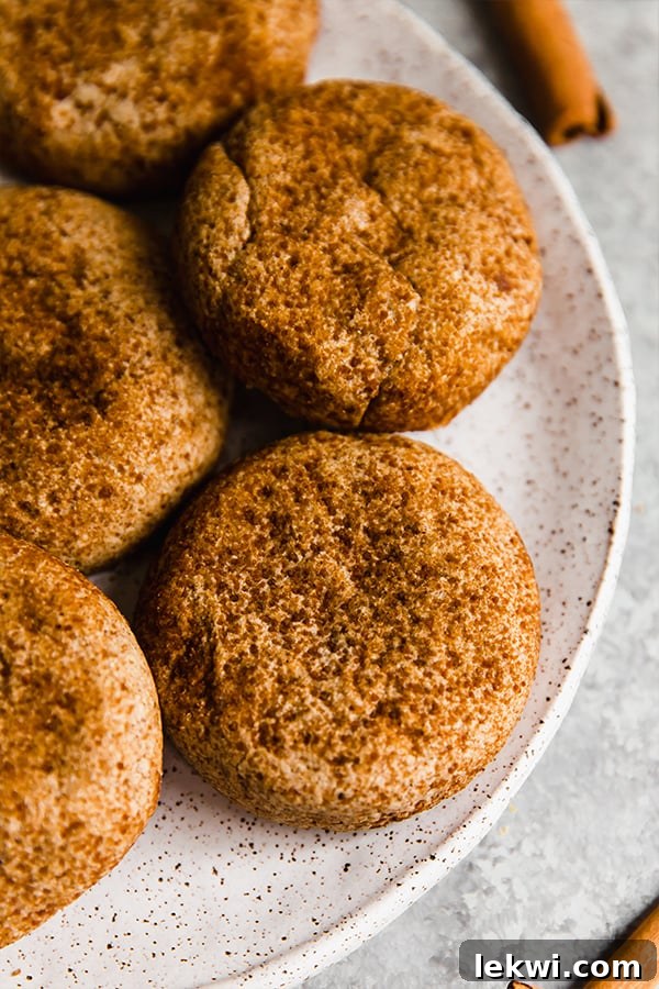 Plate of chai snickerdoodle cookies. Golden brown cookies covered in a spiced sugar mixture, stacked on a white plate with a warm, inviting glow.